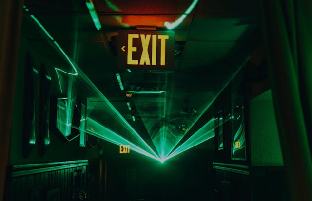 Image of an illuminated exit sign at The Flower Shop NYC venue, featuring neon green lasers taken during Perion's NFT NYC activation event.